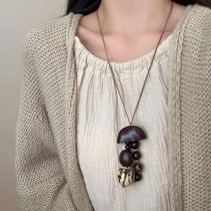 Lange vintage ketting met notendop hanger en natuurlijke plantenzaden aan koord