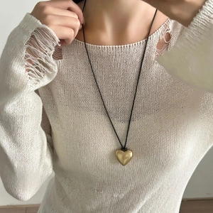 Minimalistische matgouden hartvormige hanger ketting aan zwart koord om de nek