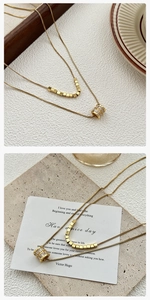 Detail van de dubbellaagse gouden ketting met kubieke kralen en een sprankelende zircon-hanger
