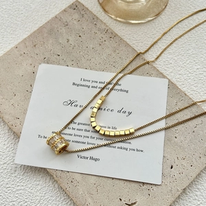 Dubbellaagse gouden titanium ketting met zirkonia cilinder hanger en kleine kubus bedels
