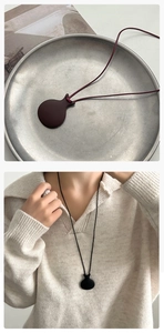 Dettaglio della collana con ciondolo a bollitore minimalista su cordini rossi e neri