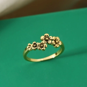 Vintage Goldring mit 3D-Blütenblättern auf einer minimalistischen dunkelgrünen Fläche