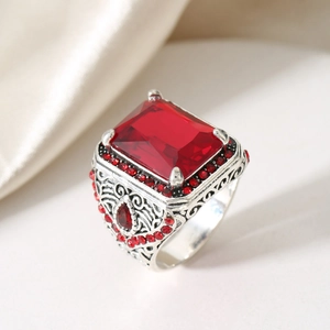 Macro detail of vintage silver ring with red rectangular zircon and intricate carvings