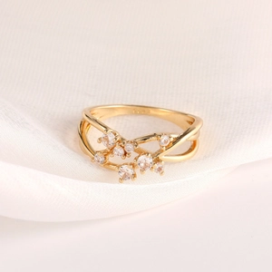 Elegant gold-plated crisscross ring with cubic zirconia stones on white textured fabric