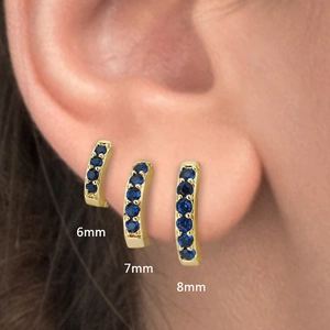 Macro shot showing comparison of 6mm, 7mm, and 8mm gold earrings with blue zircons