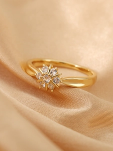Vista macro de un anillo de flor dorado con circonitas sobre satén color champán