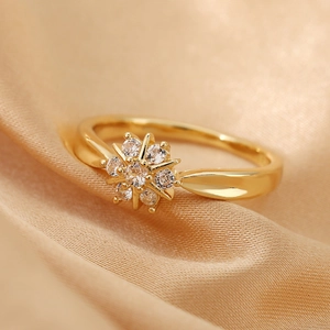 Anillo de lujo con flor dorada y cristales brillantes sobre fondo de seda
