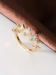 Detail of gold ring with five square-cut clear gemstones in a precise claw setting