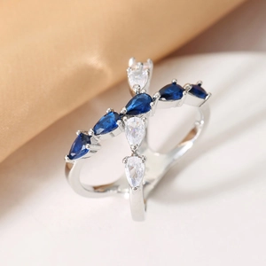 Elegant crisscross silver ring featuring blue and white pear-cut gemstones on silk