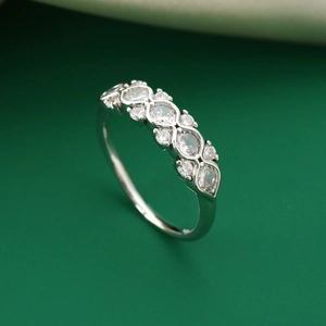 Eleganter silberner Ring mit gewelltem Steinbesatz auf dunkelgrünem Hintergrund