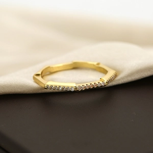 Macro shot of gold geometric bamboo ring with pavé-set zircons on warm textile backdrop