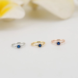 Tre anelli delicati in argento, oro e oro rosa con una pietra zaffiro blu centrale