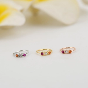Dettaglio dei piercing al naso con zirconi colorati in finiture argento, oro e rosa