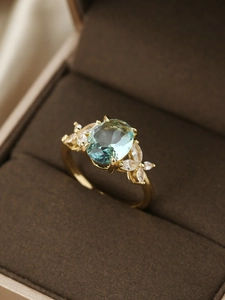 Dettaglio macro dell'anello con pietra ovale celeste placcato oro e zirconi bianchi marquise