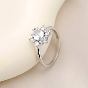 Vista macro di un anello a girasole in argento con zirconi rotondi e finitura brillante