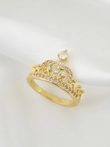 Macro shot of gold-plated crown ring with white cubic zirconia on white silk