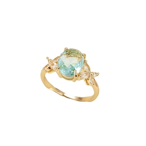 Elegante anello d'oro con una grande pietra blu ovale e pietre laterali marquise su sfondo bianco
