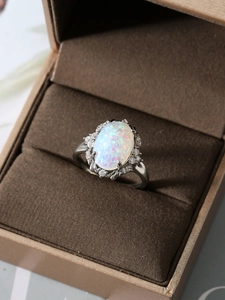 Macro view of oval opal ring with diamond halo presented in a premium velvet gift box