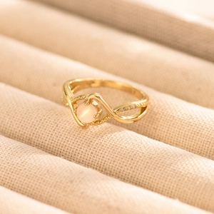 Macro shot of gold cross ring with pink moonstone and delicate zircon details