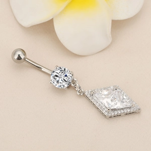 Macro detail of diamond-studded rhombus belly ring with hanging crystal and silver bar