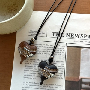 Detail of silver wrapped wood heart pendants on vintage newspaper background