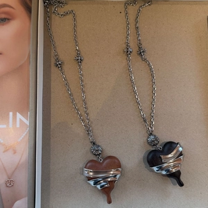 Detail view of heart-shaped ebony wood pendants with wrapped silver metal edge accents