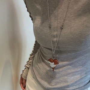 Detail of vintage heart ebony pendant on a silver necklace worn over a grey sweater