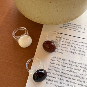 Gros plan de bagues en résine ovale translucide en blanc, ambre marron et noir