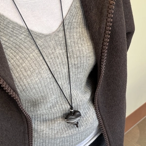 Detail view of heart-shaped ebony pendant with silver wire wrap on model neck