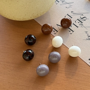 Nahaufnahme minimalistischer Kugelstecker aus Kunstharz in neutralen Erdtönen auf Holz