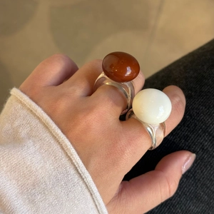 Grosses bagues acryliques transparentes avec résine brune et perle blanche sur la main