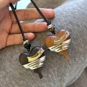 Detail view of heart-shaped ebony wood pendants with wrapped silver metal on black cord
