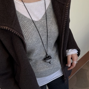 Close-up of heart-shaped black ebony pendant necklace on a model with wool coat
