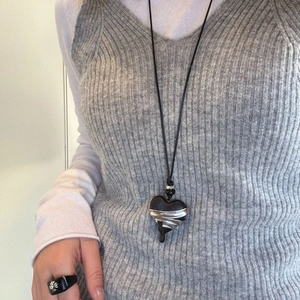 Close-up of vintage ebony heart necklace and floral cross ring on a female model