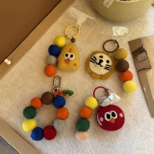 Close-up of handmade wool felt bird and lion charms with colorful beaded phone chains