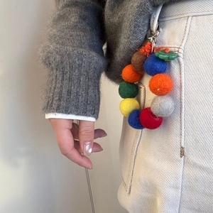 Handmade colorful wool felt ball keychain loop hanging on casual trousers for style