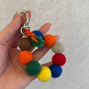 Detailed macro view of colorful felt balls and floral charm on a sturdy metal clip