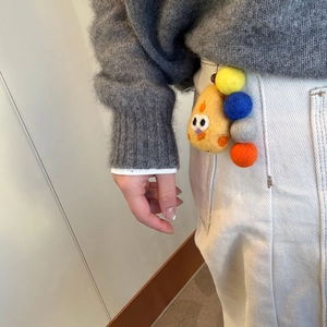 Handmade yellow wool felt pear phone charm attached to white corduroy trousers