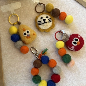 Detailed macro view of handmade wool felt lion and chick charms with beaded lanyard