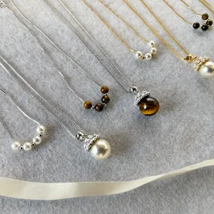 Λήψη flat lay από κολιέ με πέρλες και πέτρα μάτι της τίγρης πάνω σε λευκό πλεκτό ύφασμα