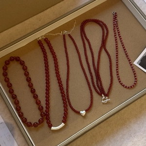 Close-up of red agate beaded necklaces with various silver charms and OT buckle detail