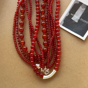 Detail of red agate beaded necklace featuring silver heart pendant and toggle clasp