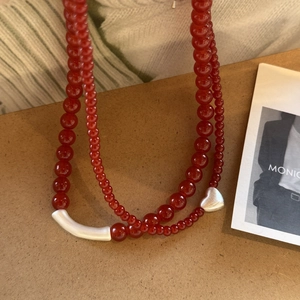 Detail of red agate beaded layered necklace with silver heart and curved tube pendant