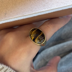 Detailopname van een vintage gouden ring met een gepolijste ovale tijgeroog op vinger