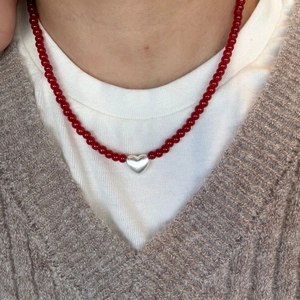Minimalist red agate bead necklace with a silver heart pendant on a stylish model