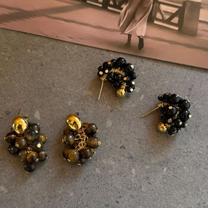 Detail van tijgeroog en zwarte obsidiaan oorbellen met gouden metalen afwerking