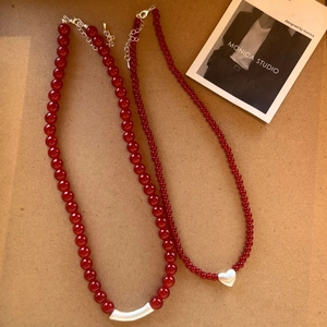 Detail view of red agate beaded necklaces with crescent tube and silver heart pendant