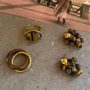 Detailweergave van vintage tijgeroog sieradenset met ringen en oorbellen op een stenen plaat