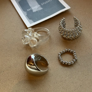 Detailansicht eines stylischen Harzblumenrings und verschiedener metallischer Ringe