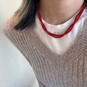Close-up of red agate beaded layered necklace worn with a V-neck sweater on a model